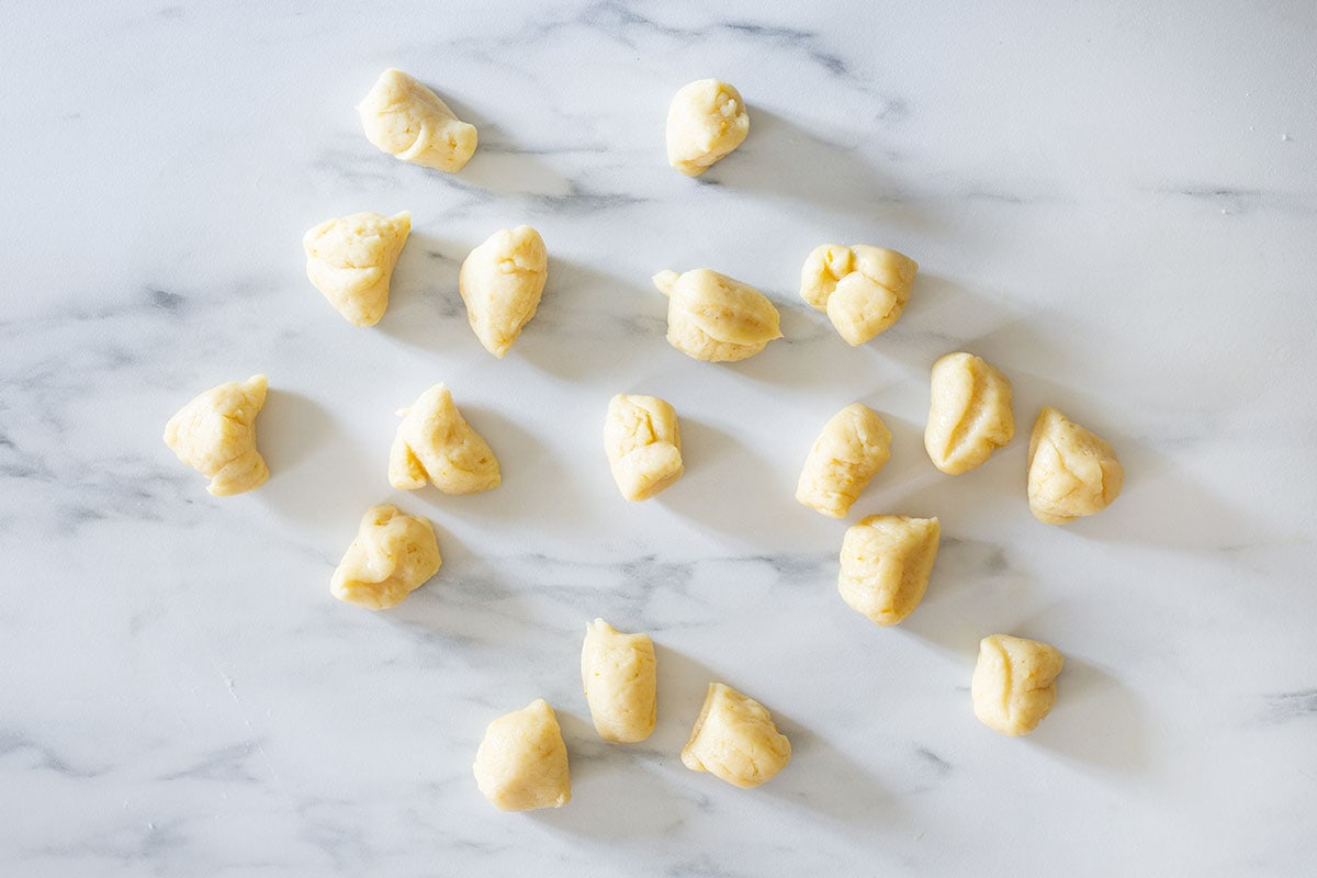 18 small pieces of dough on a kitchen countertop.