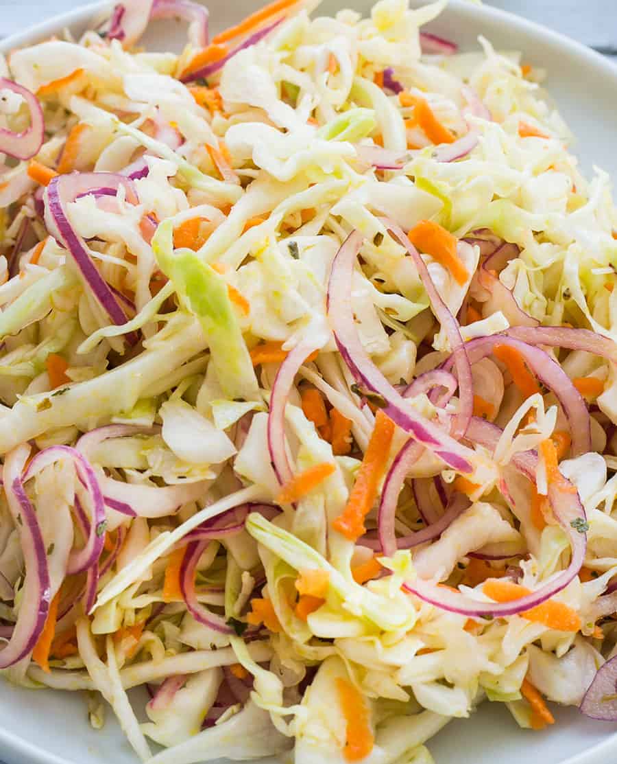 Fresh salad with onions, cabbage and carrots on a white bowl.