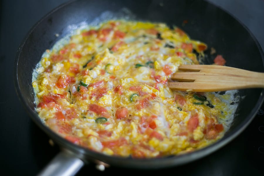 Scrambling the eggs with the other ingredients on the pan.