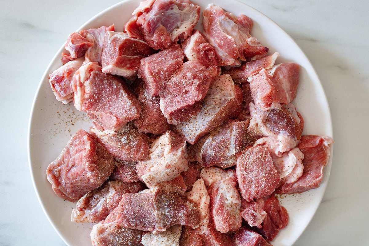 Beef chunks in a plate seasoned with salt and pepper.
