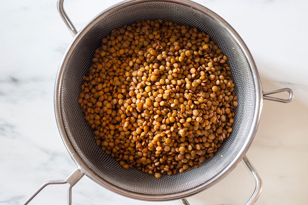 Cooked lentils on a strainer.
