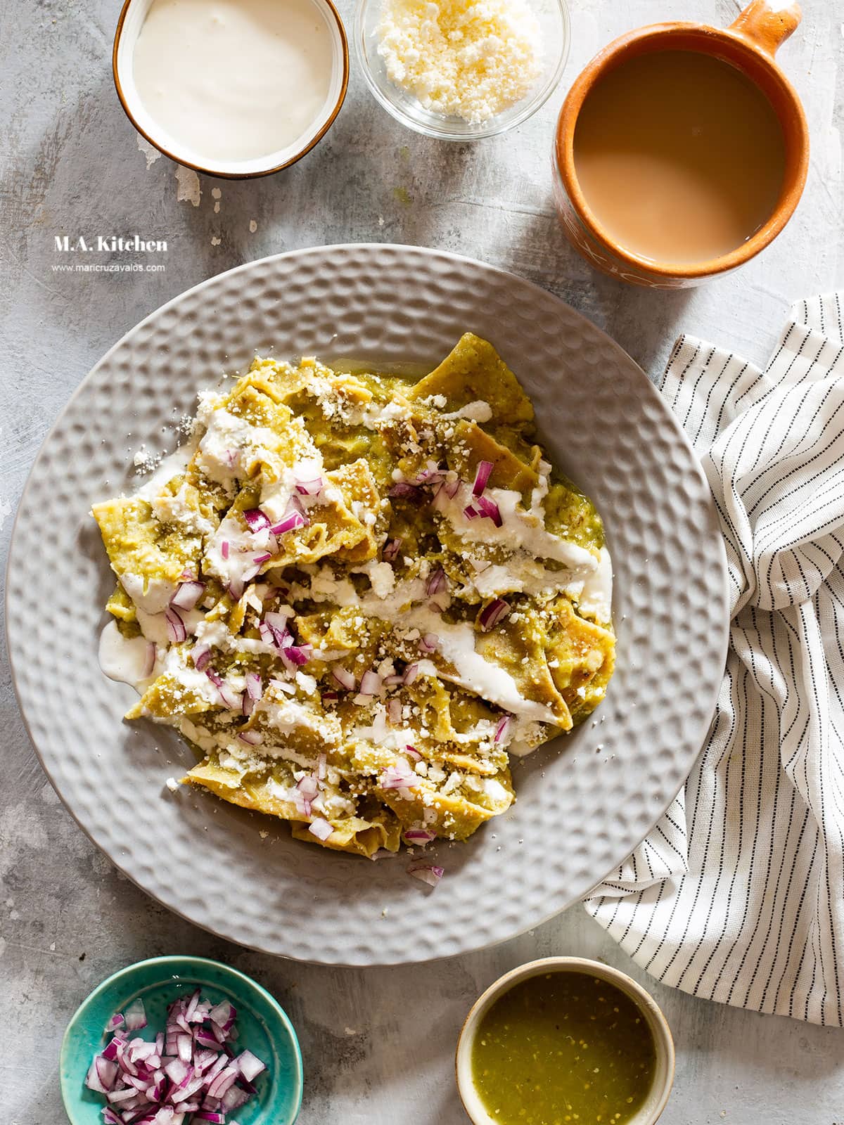 Chilaquiles verdes on a plate, more toppings on the side and a cup of cafe con leche.