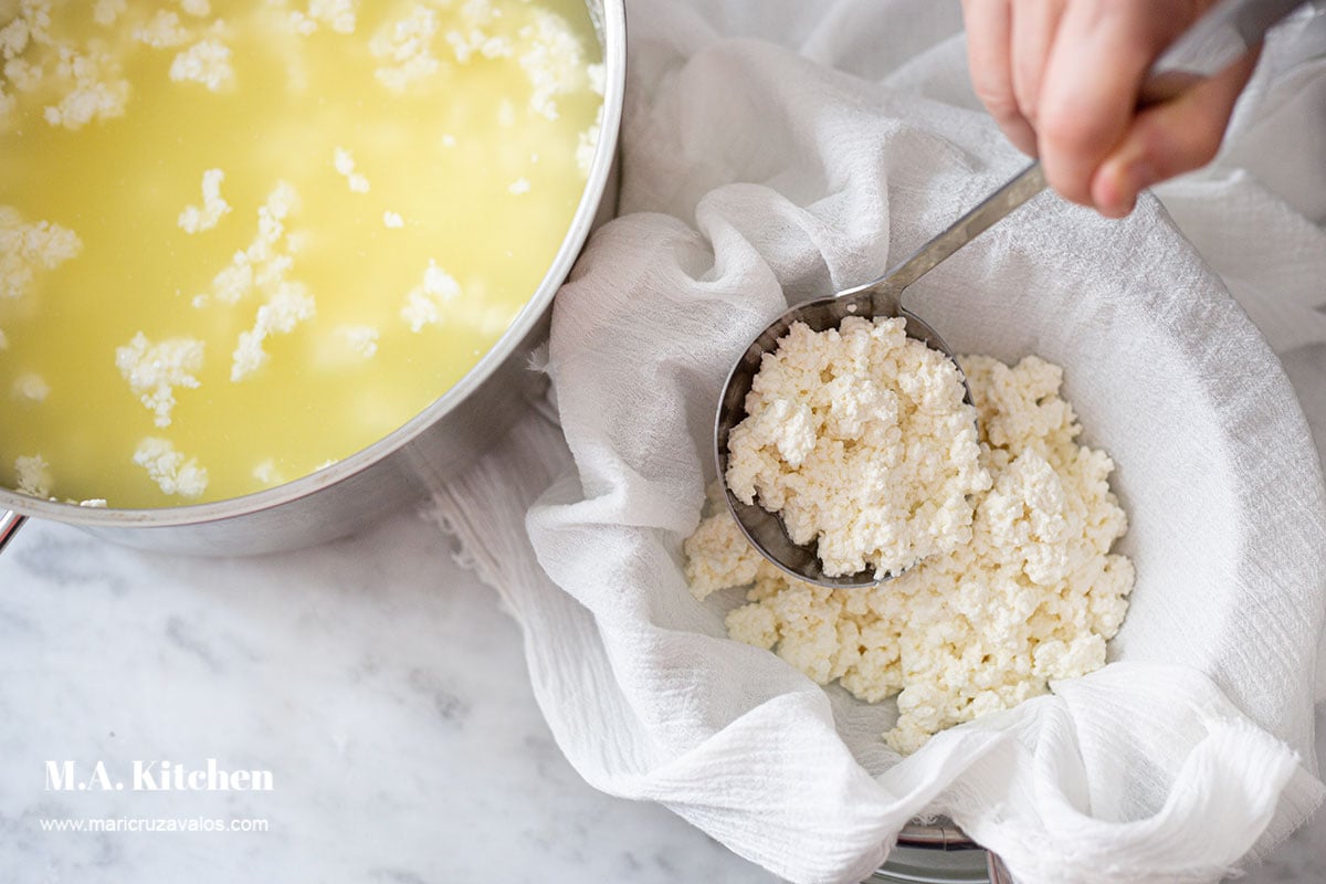 Placing the milk curds in a colander lined with cheesecloth.