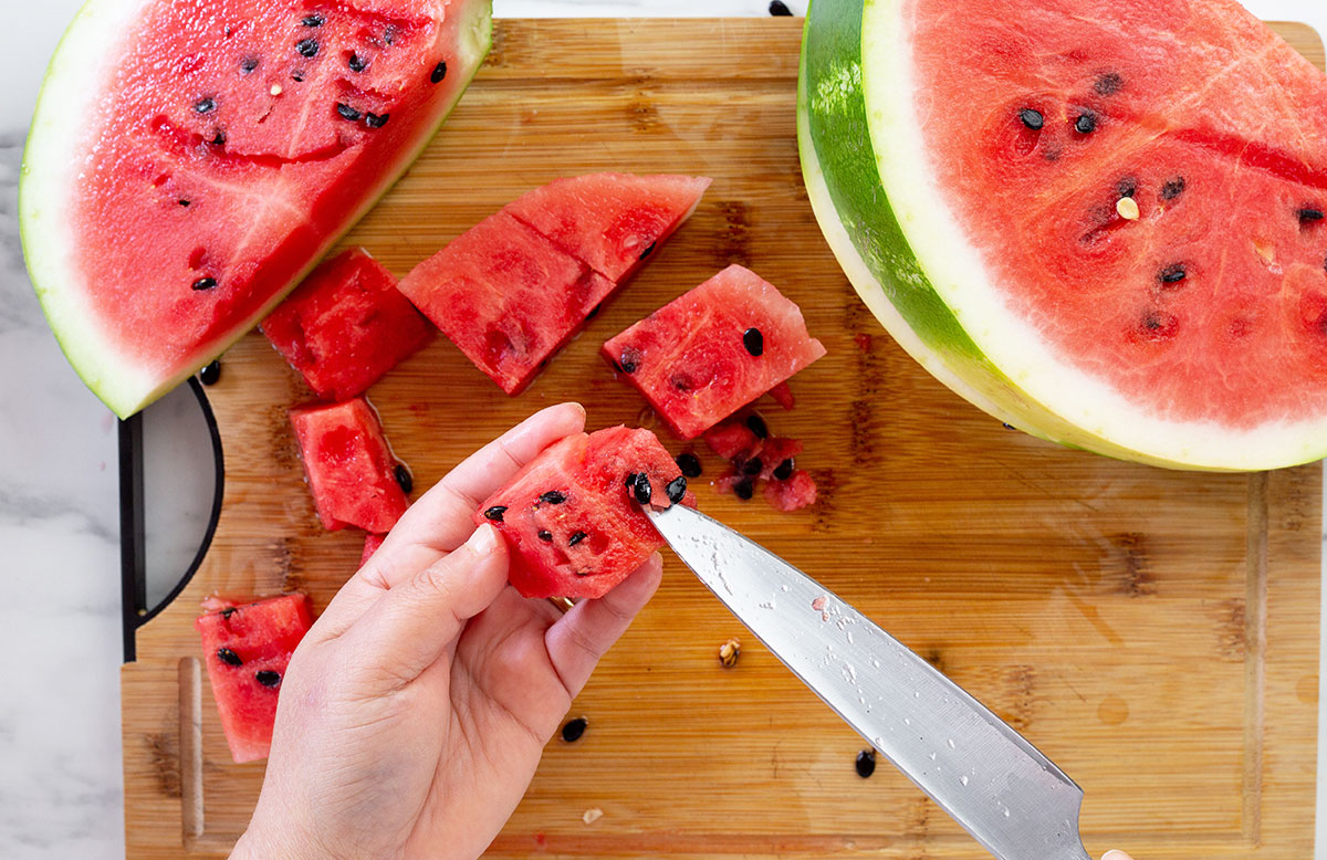 Cutting watermelon and discarding the seeds.