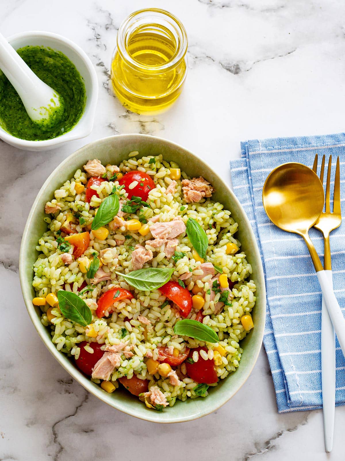 Pesto rice salad on a bowl with some ingredients scattered around.