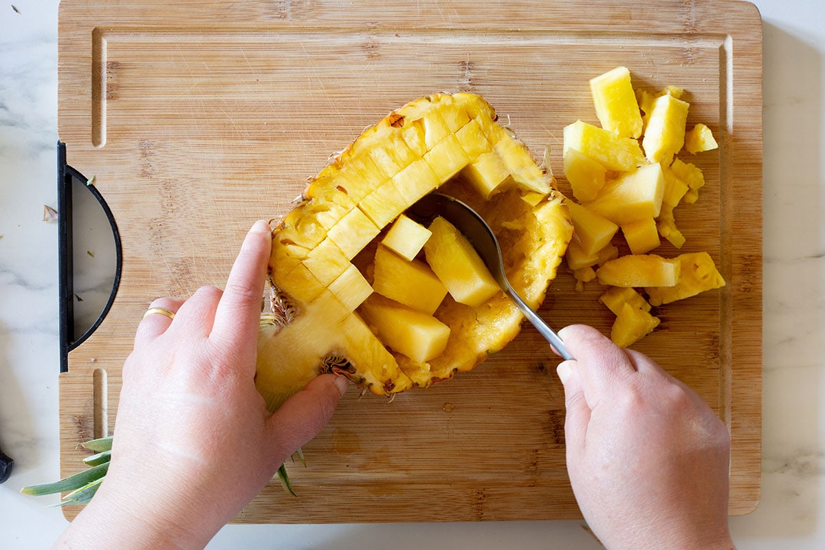 Scooping up the flesh off the pineapple.
