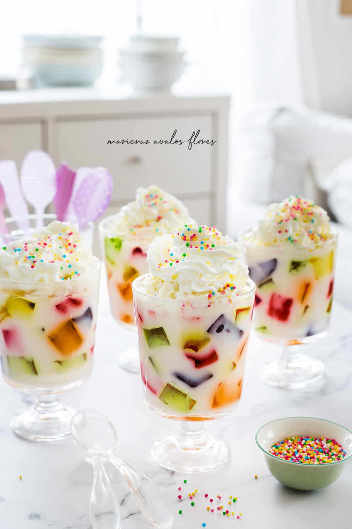 Mexican mosaic jello, gelatina de mosaico, in cups and garnished with whipping cream and colorful sprinkles.
