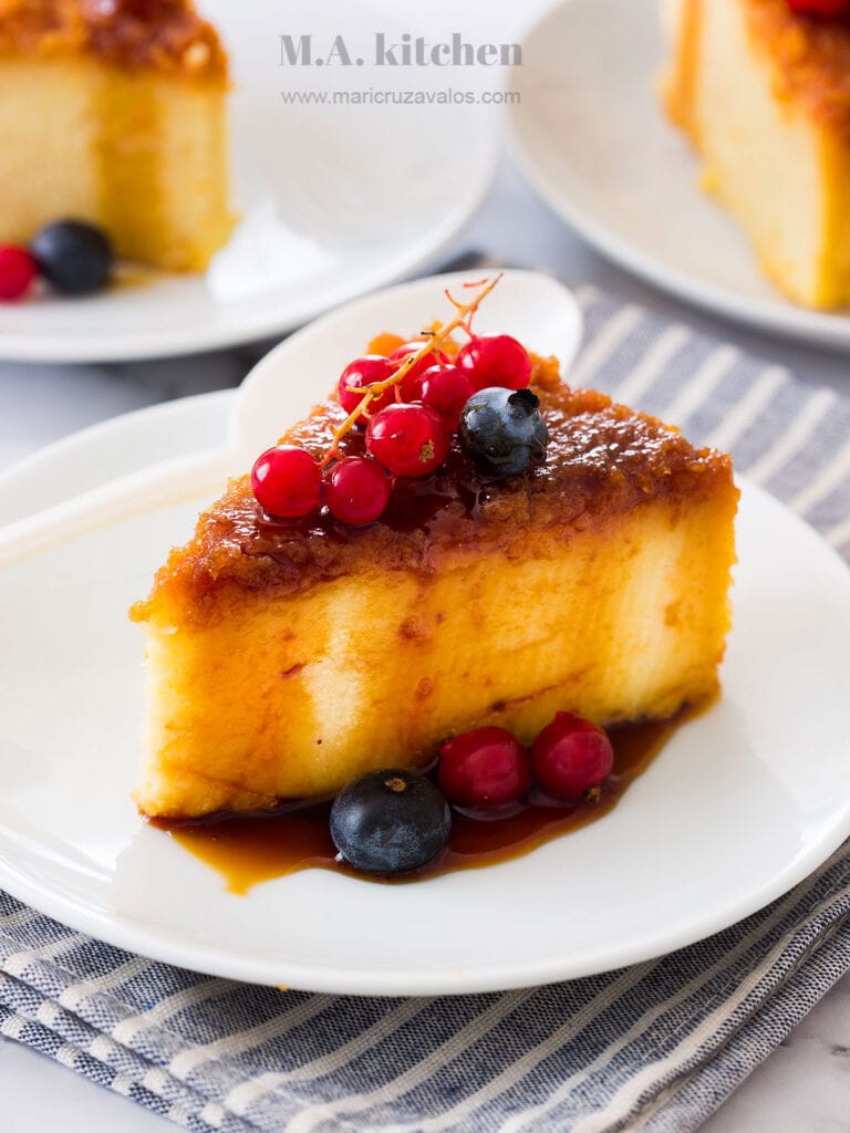 A slice of budin de pan served with berries and caramel on top.