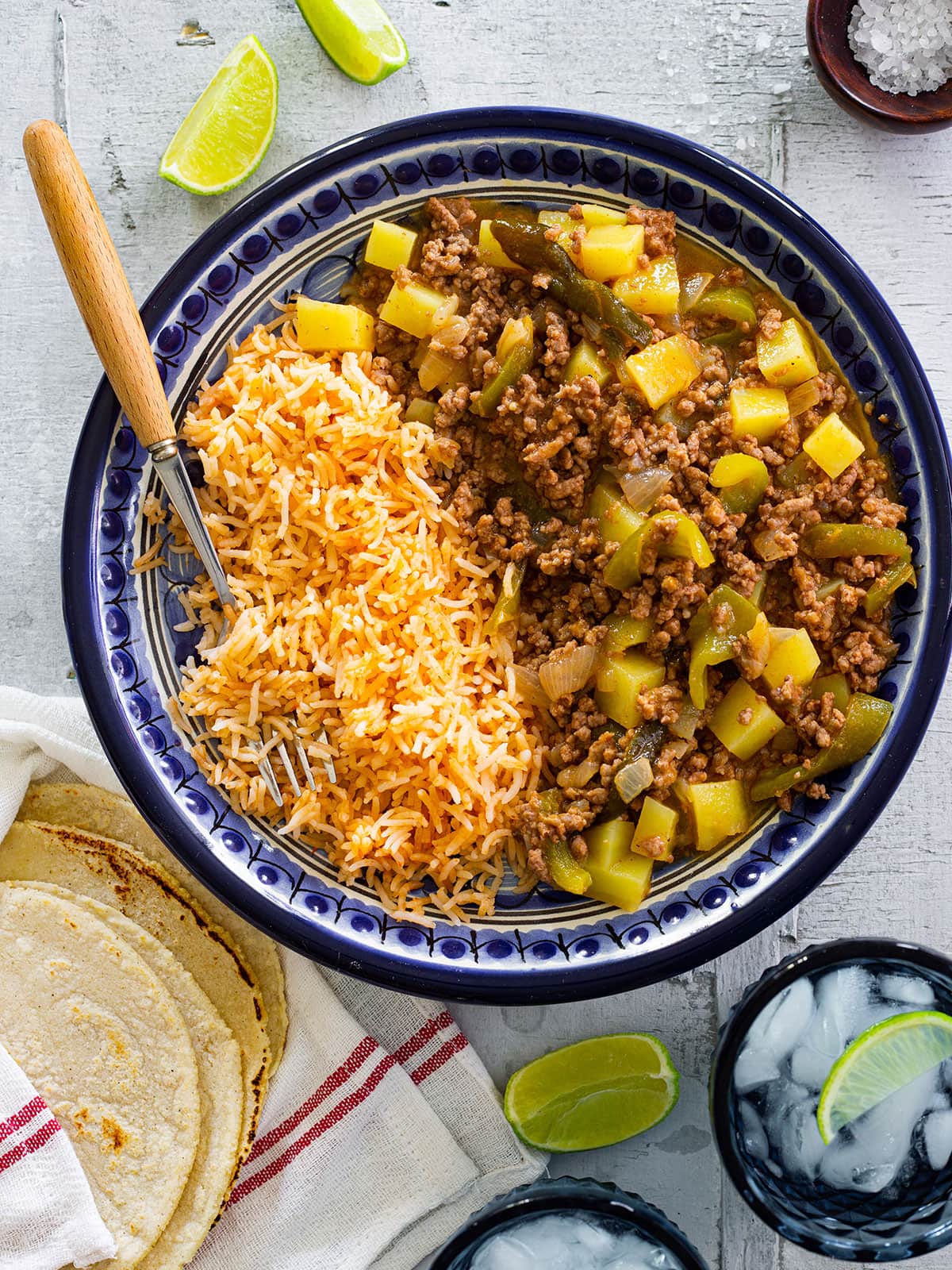 Mexican Picadillo with potatoes served on a plate with rice and tortillas.