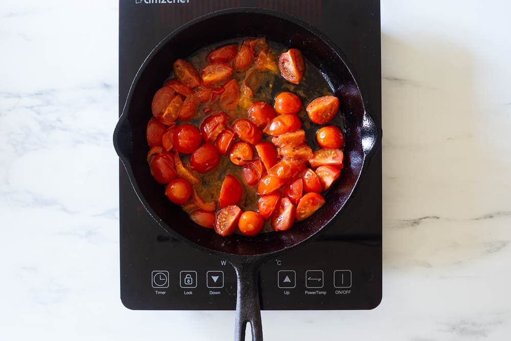Cherry tomatoes cooking on a cast-iron skillet to make gnocchi alla sorrentina.