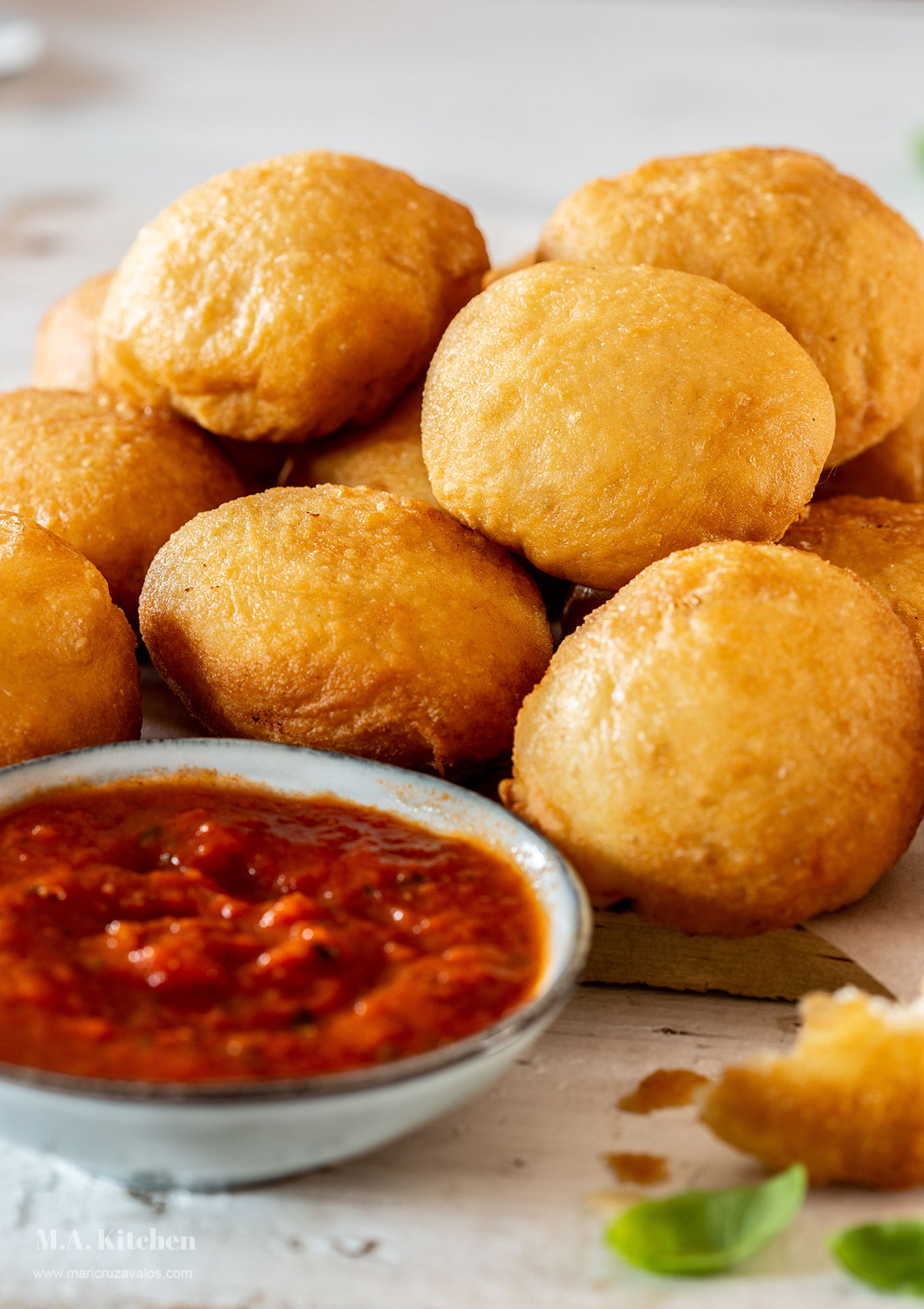 Fried pizza dough balls piled with marinara sauce on the side.