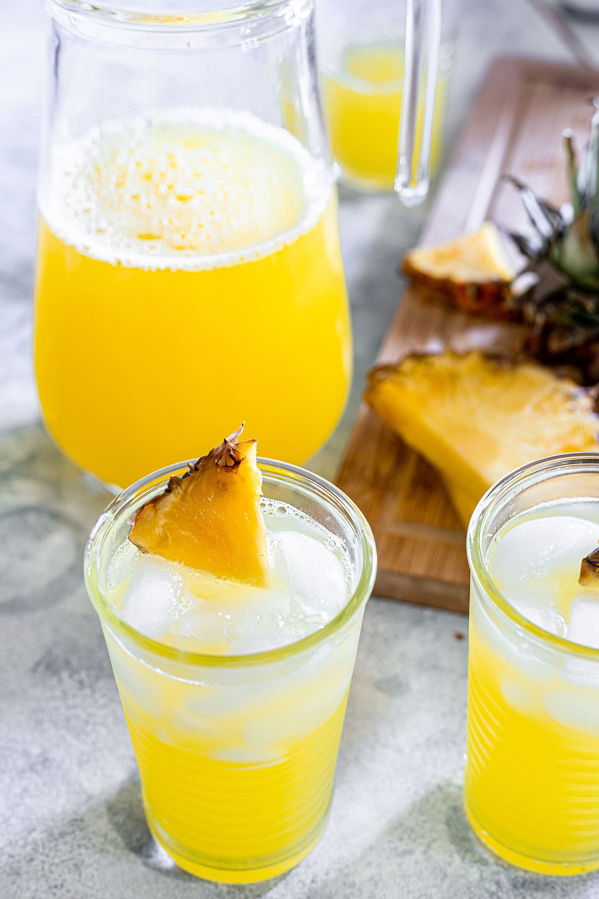 Pineapple agua fresca, also known as agua de piña in glasses and a pitcher in the background.