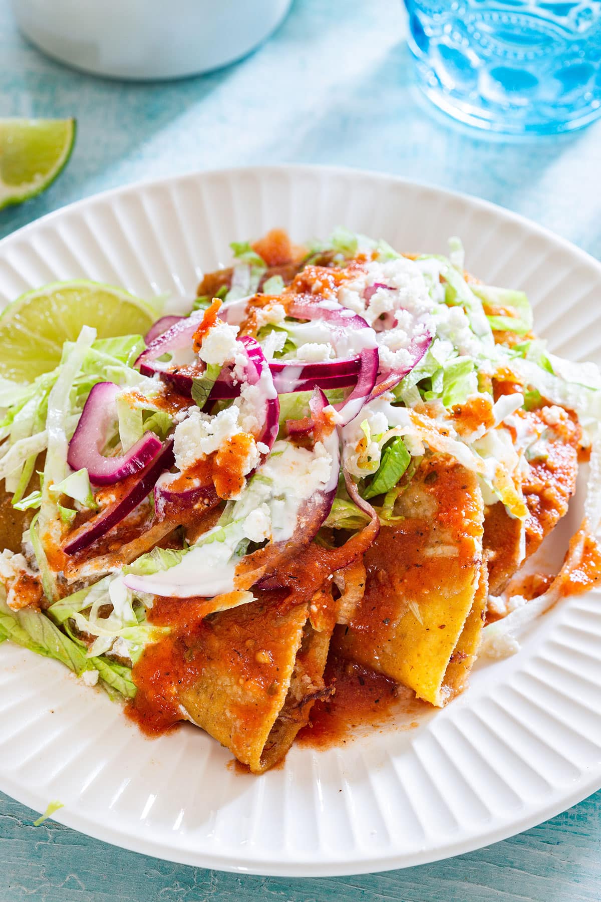Deep fried tacos dorados served with lettuce, salsa, cheese, cream, and pickled onions.
