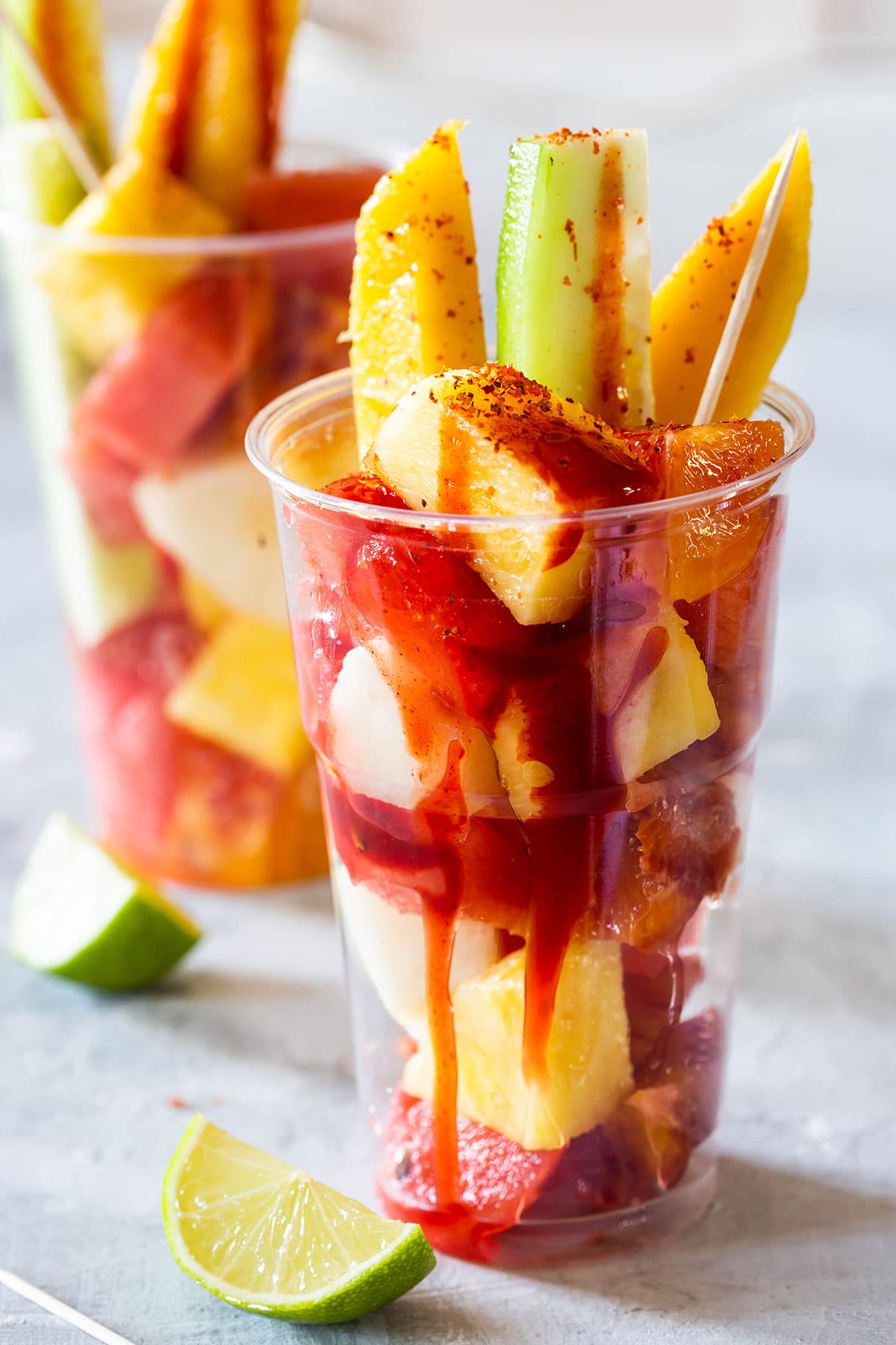 Mexican fruit cups garnished with salsa, chili powder and lime juice.