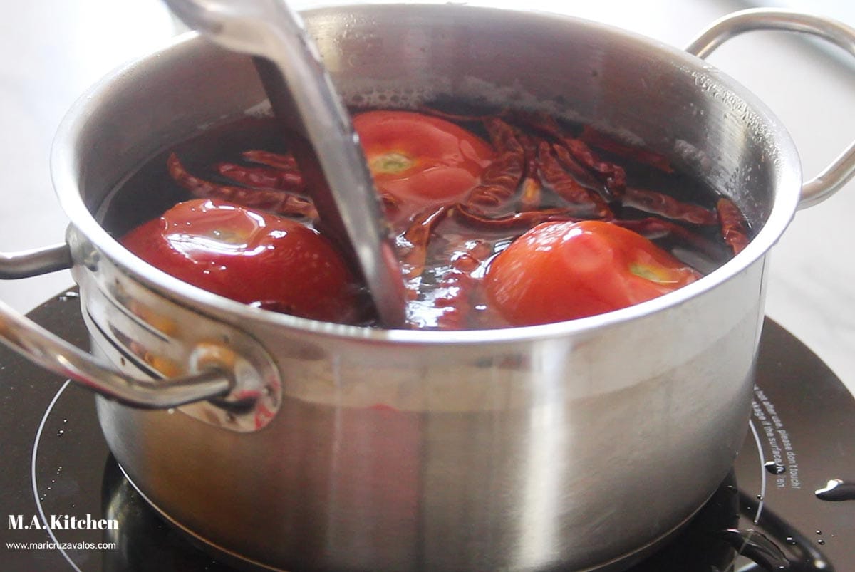 Adding chile de arbol to the pot.
