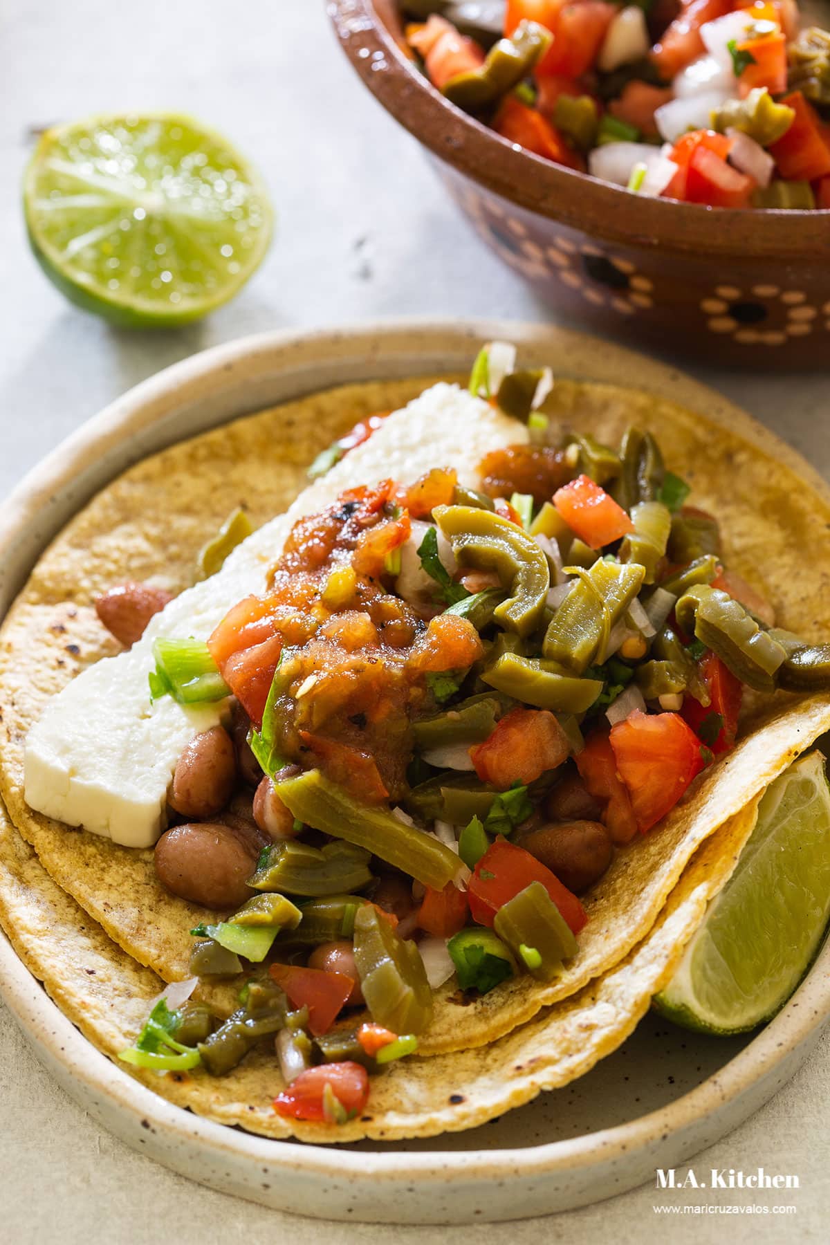A taco made with corn tortilla, nopales salad, beans, queso fresco and salsa.
