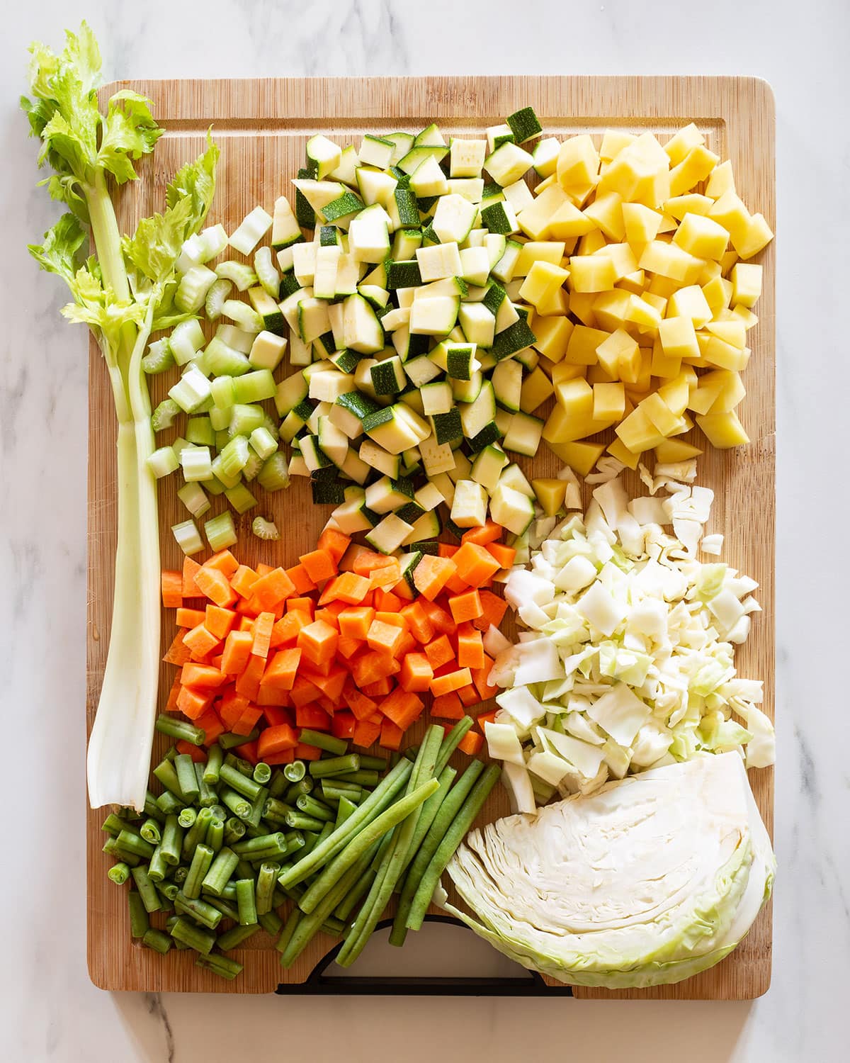 Various vegetables for sopa de verduras cut and arranged on a cutting board.