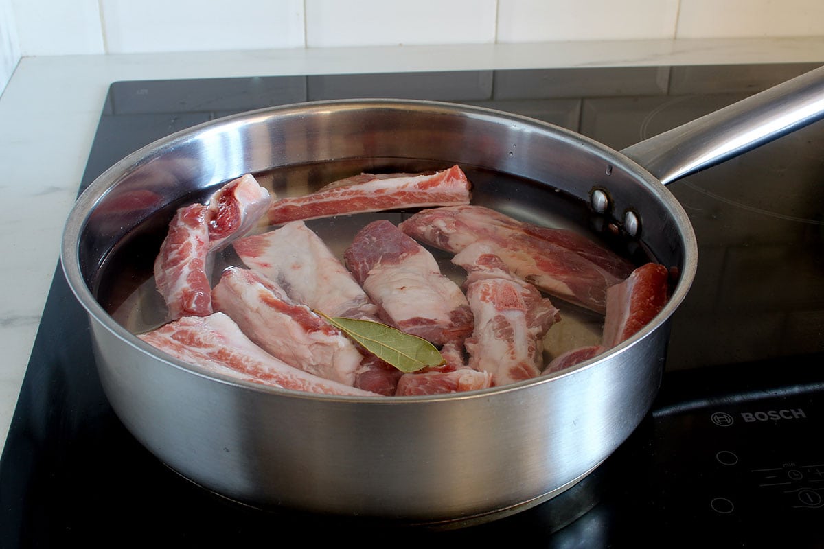 Pork ribs slightly covered with water in a deep pan, ready for cooking.
