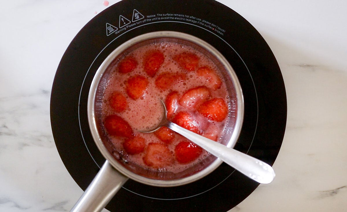 Fresh strawberries and sugar cooked in a saucepan.