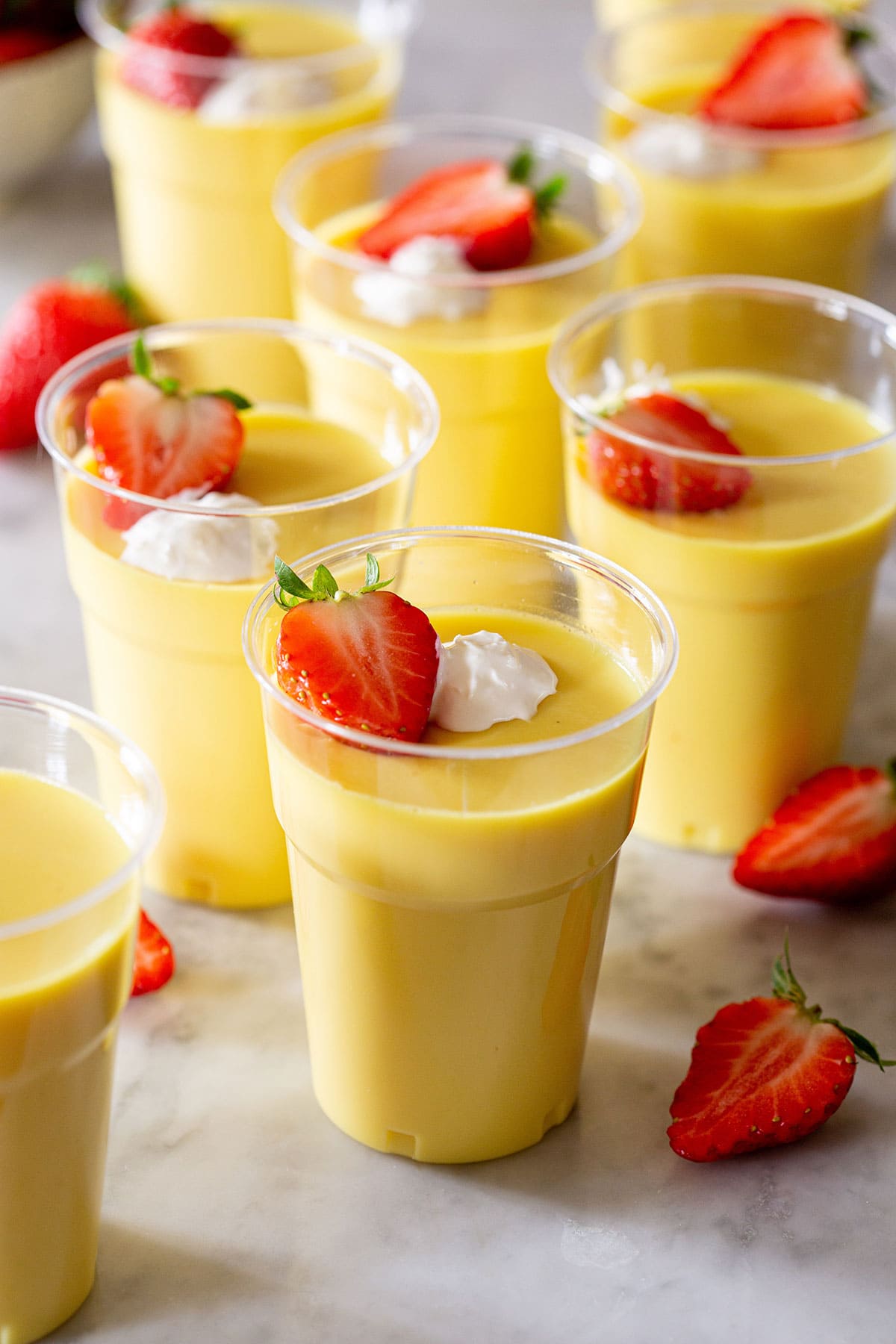 Gelatina de rompope in cups garnished with fresh strawberries and whipped cream.