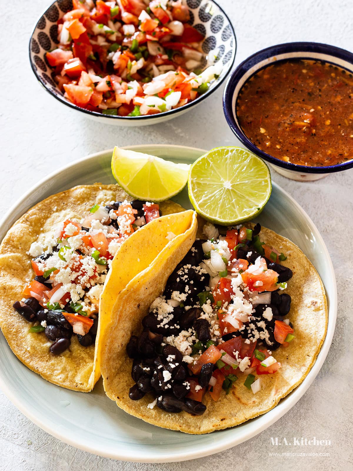 Mexican black beans tacos with pico de gallo salsa, queso fresco, and roasted salsa. Served in a plate.
