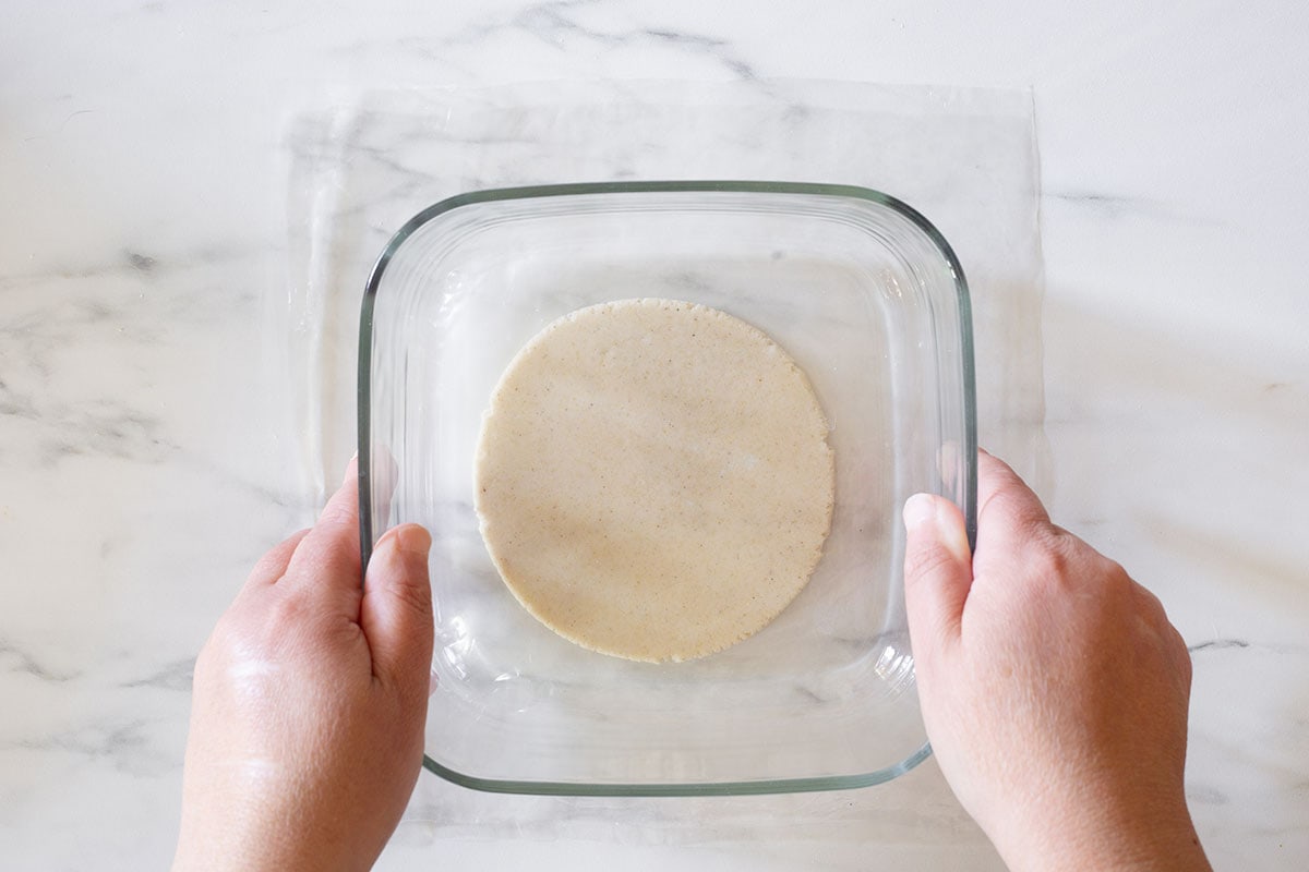 Pressing the dough with a heavy dish to make a gordita.