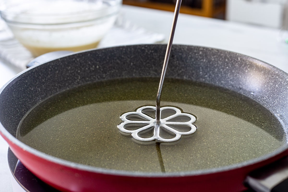 the rosette mold immersed into the oil in a pan.