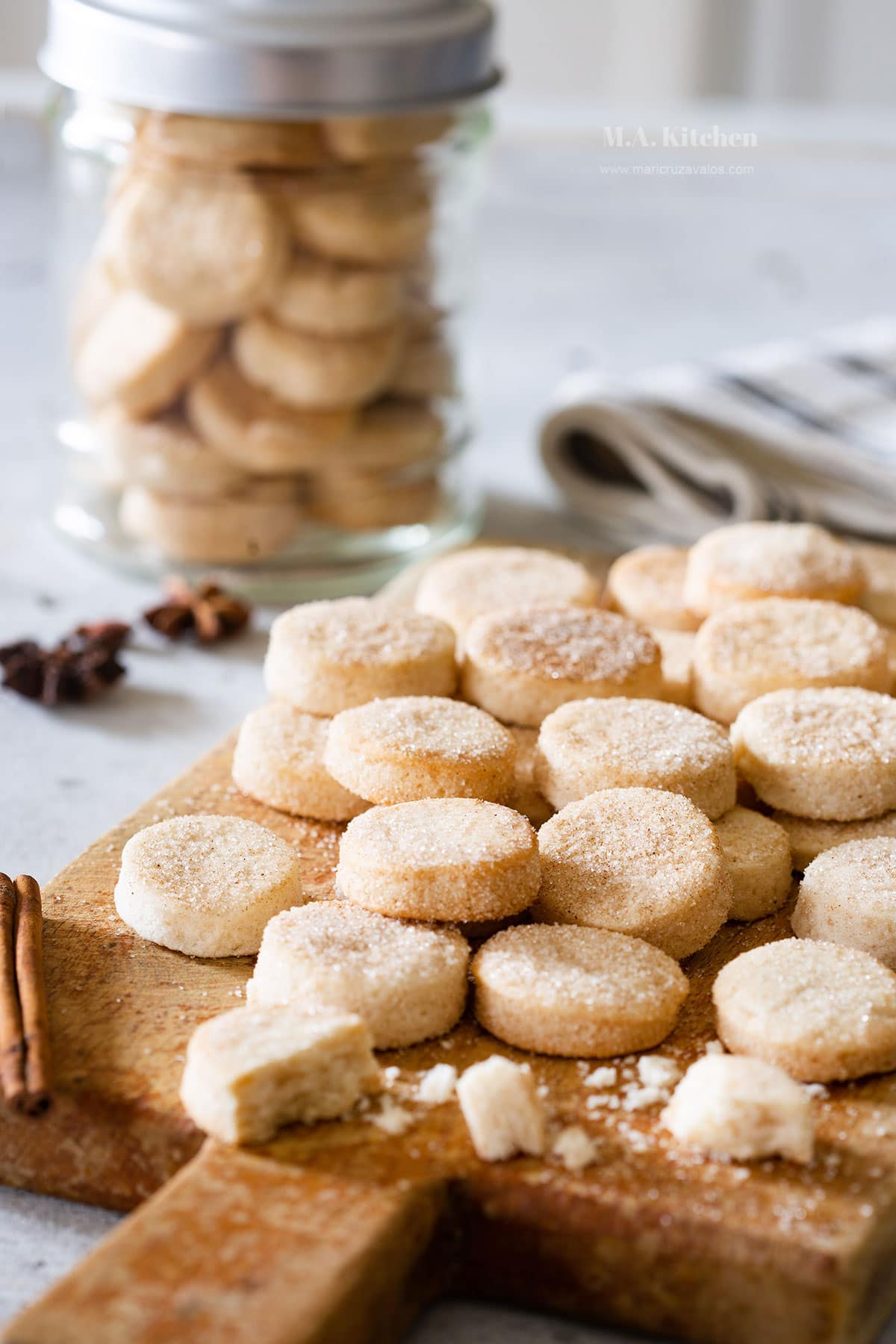 Pan de Polvo, aka Mexican shortbread cookies, placed on a cutting board and a cookie jar.