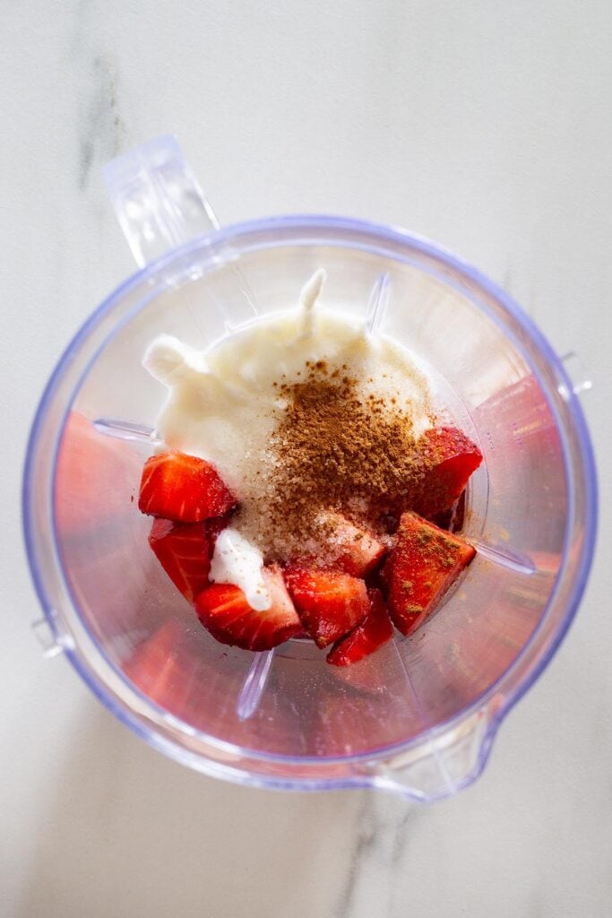 Strawberries, yogurt, sugar, and ground cinnamon in a blender.