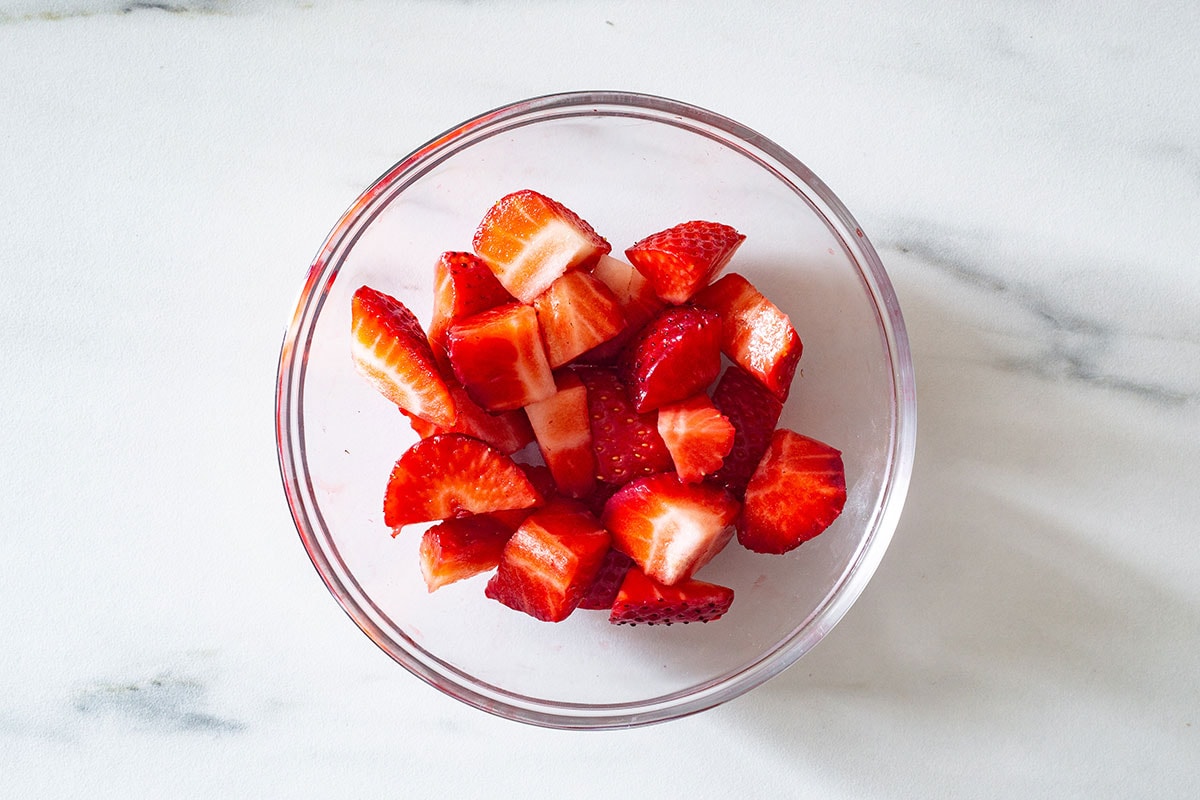 Fresh strawberries cut into small chunks in a bowl.