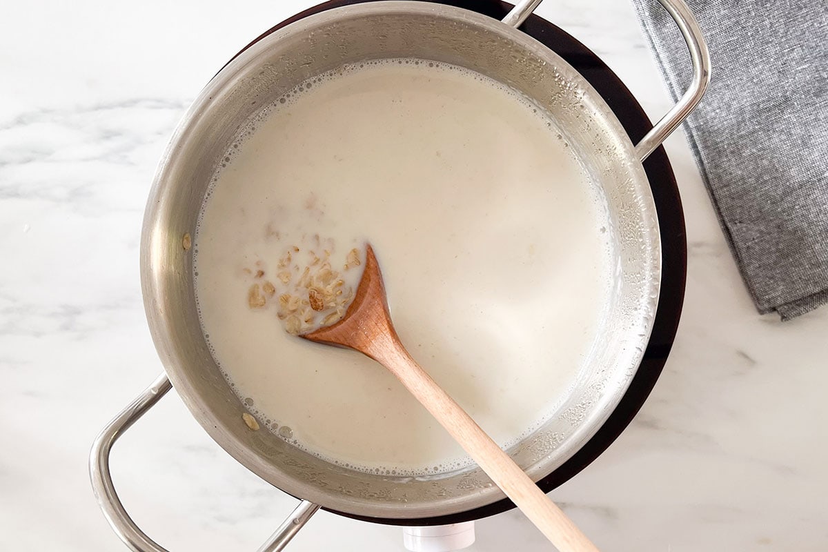 Milk added to a pot with avena, water, and cinnamon stick.