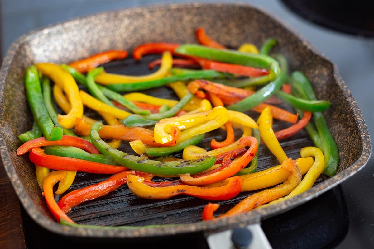 Cooking bell peppers strips in a griddle.