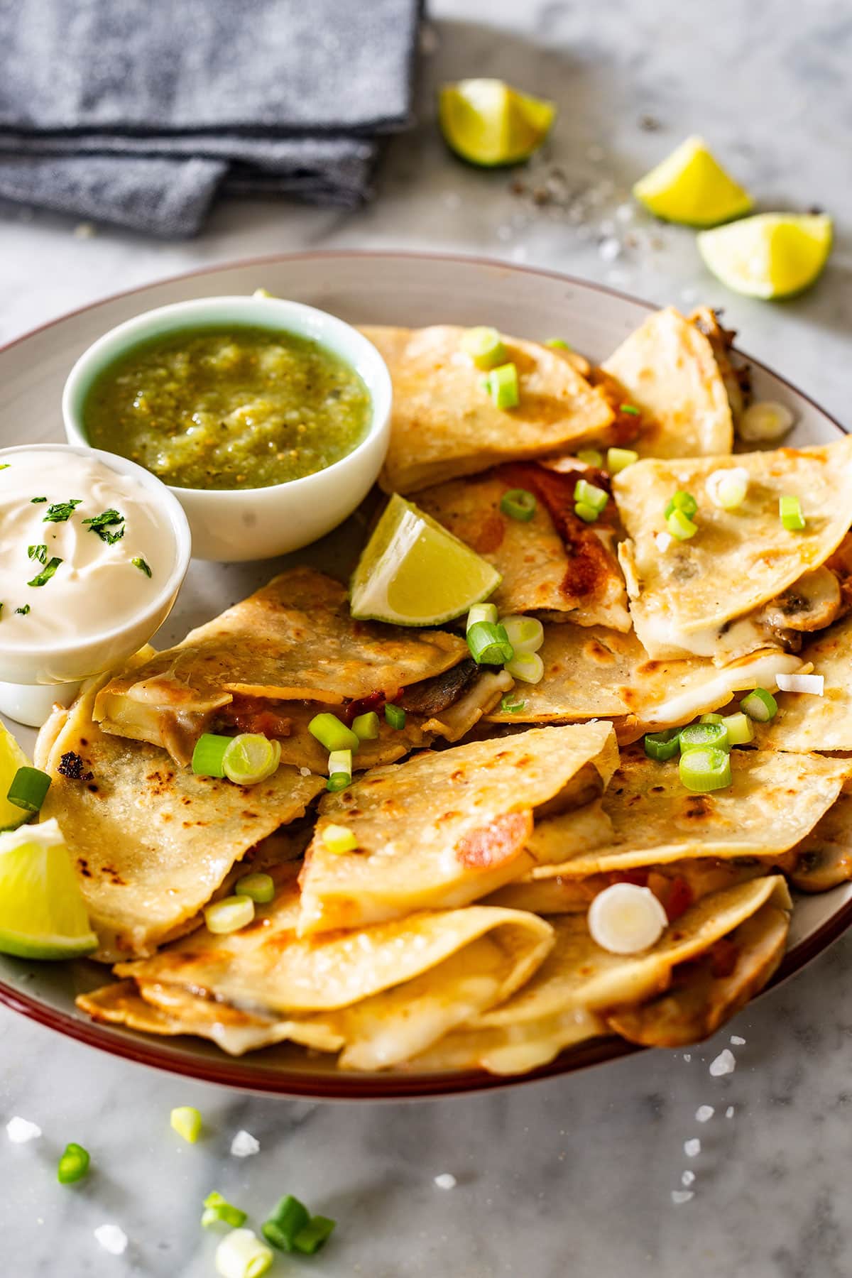 Quesadillas de champiñones on a plate with salsa and sour cream.
