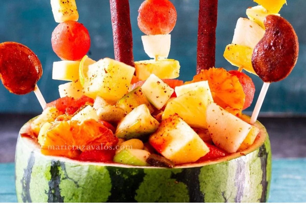Shell of watermelon with various fresh fruits, salty snacks, and Mexican candies.