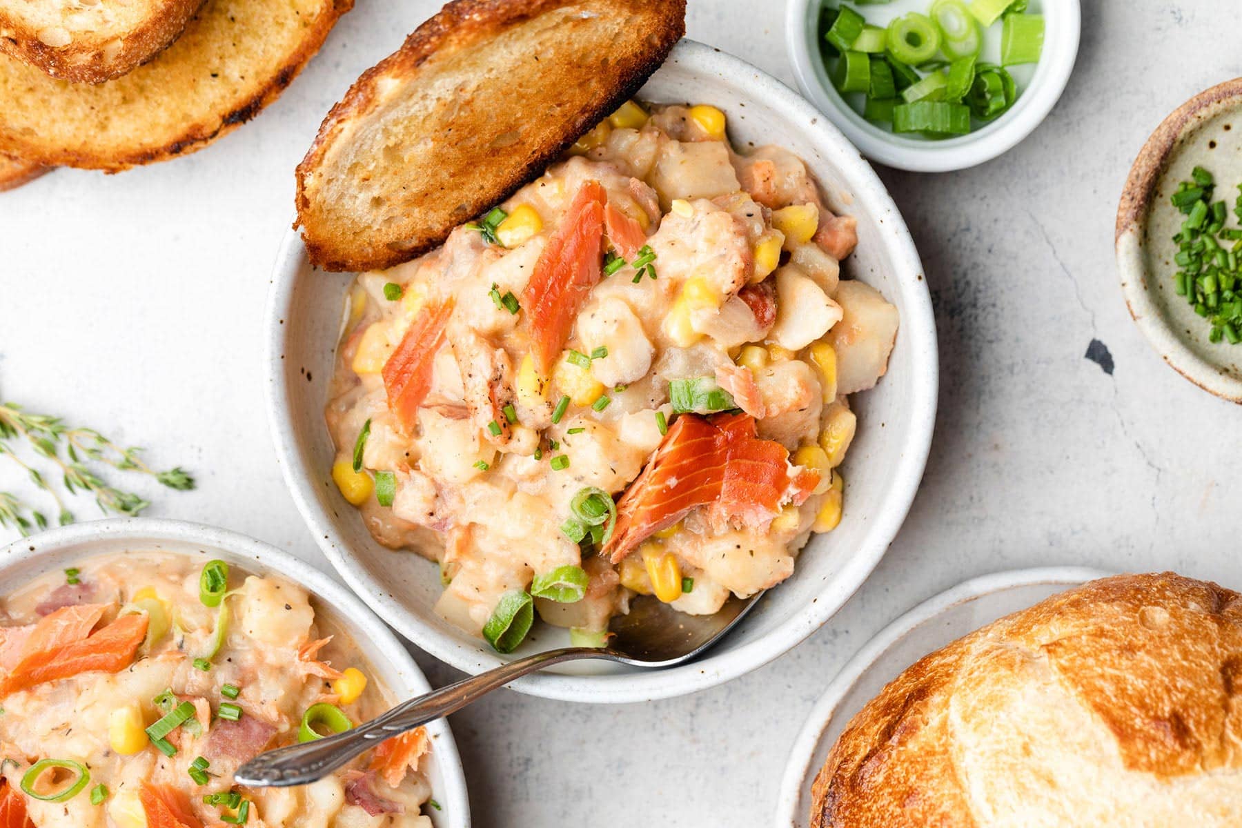 Smoked salmon corn chowder in bowls and bread on the side.