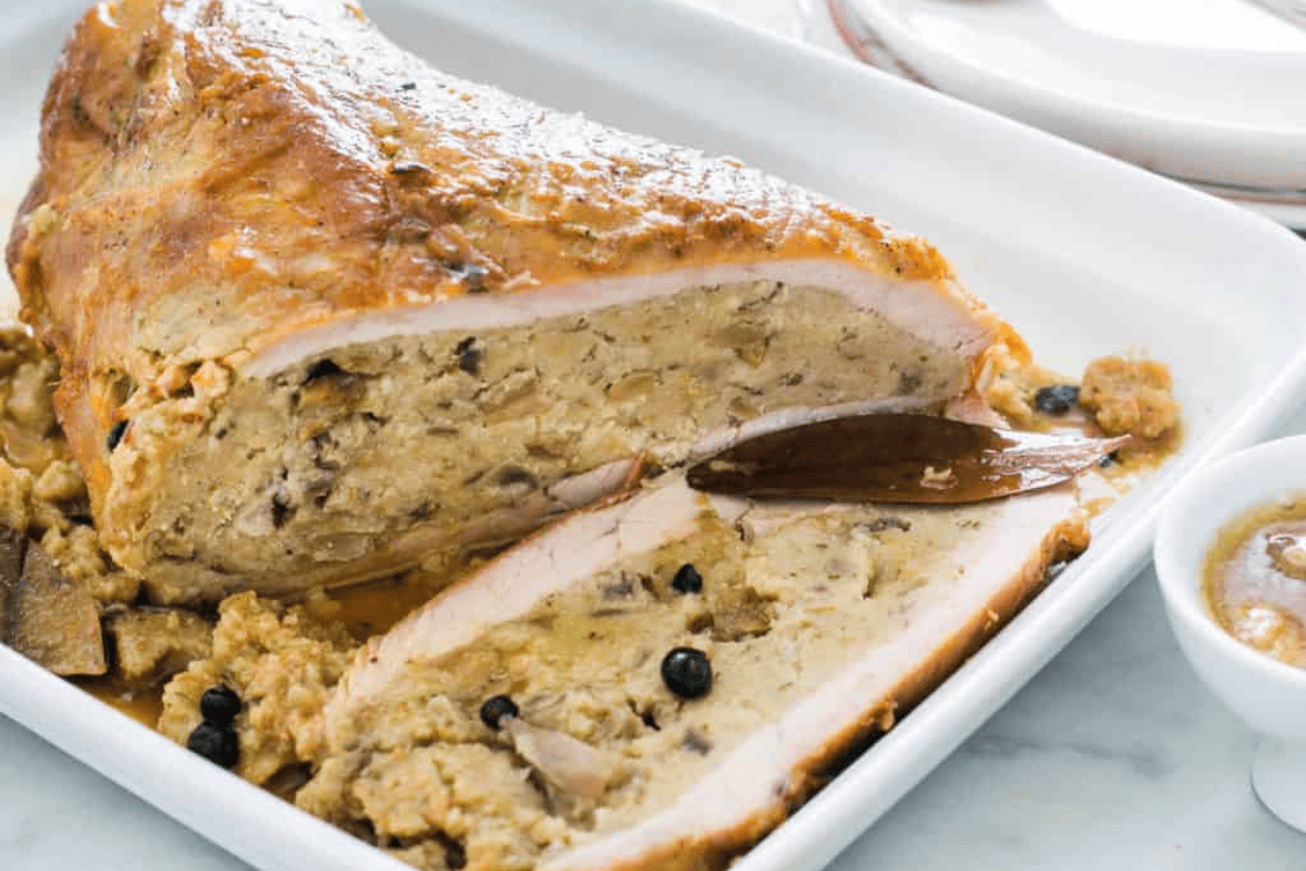 Sliced veal pocket stuffed with mushrooms and bread on a rectangular plate.
