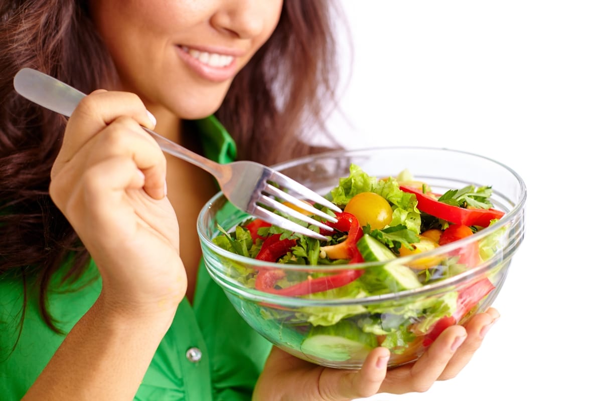 A woman eating a salad with a fork.