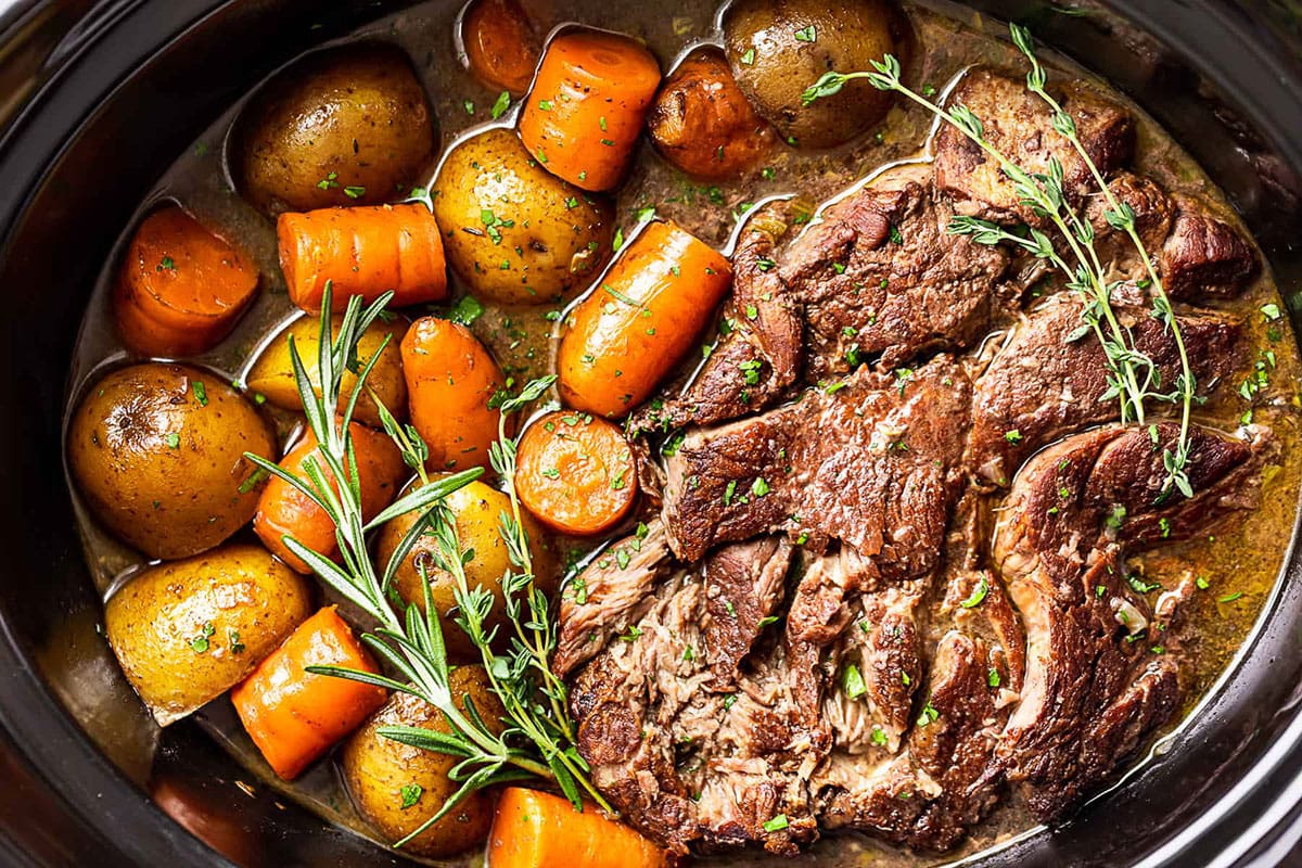 Slow cooker pot roast with vegetables and garnish.
