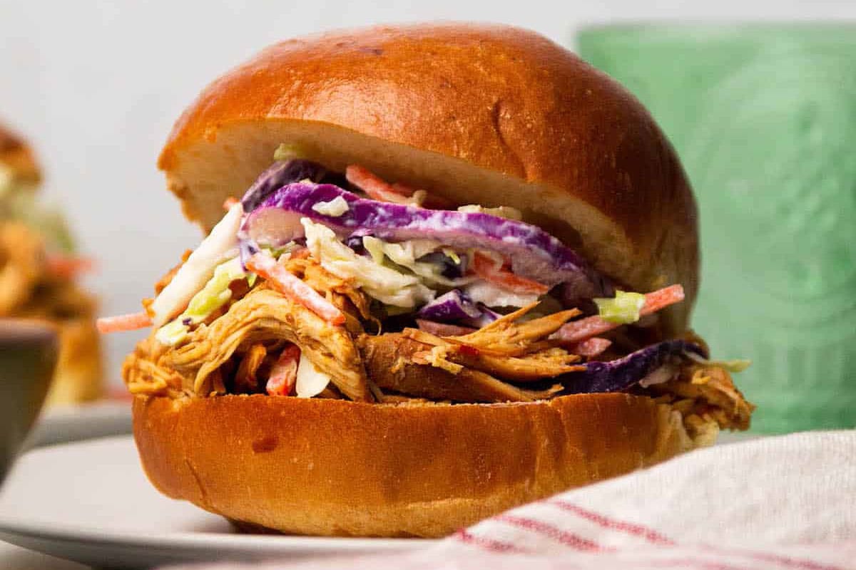 A sandwich of bbq shredded chicken with coleslaw.