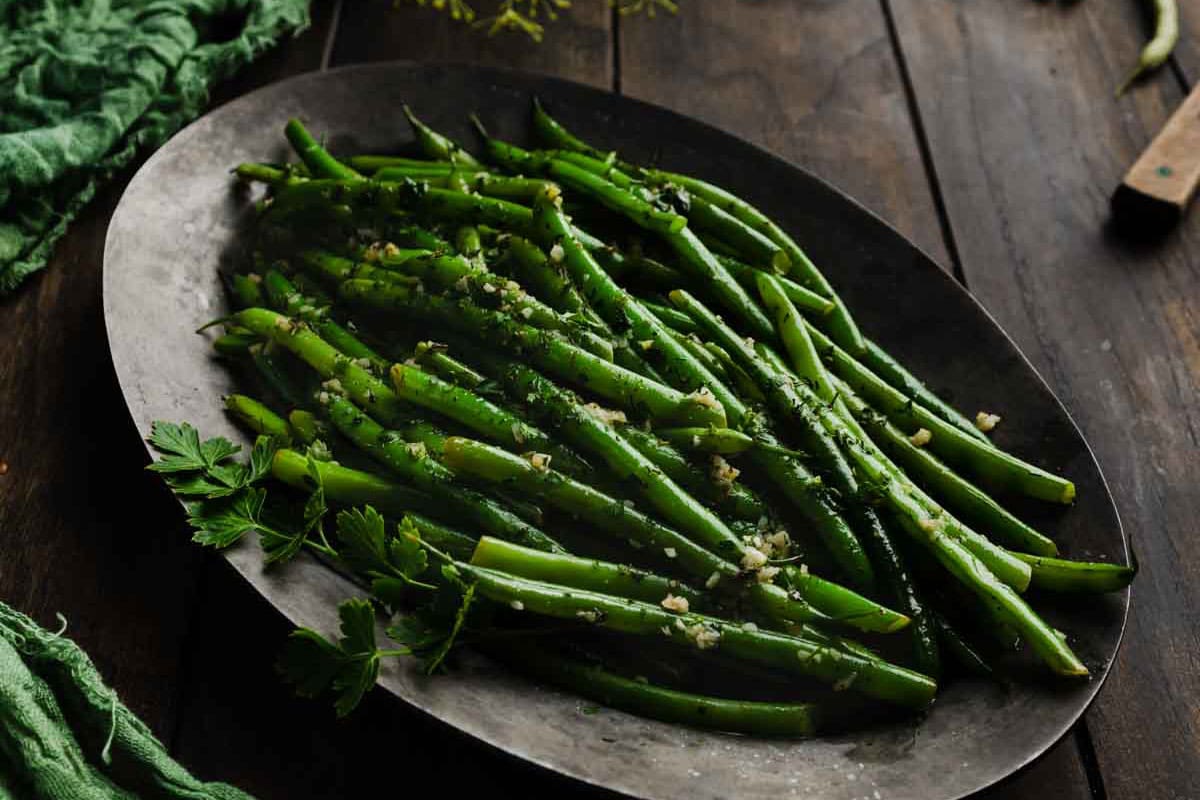French-style green beans in garlicky herb butter on a plate.
