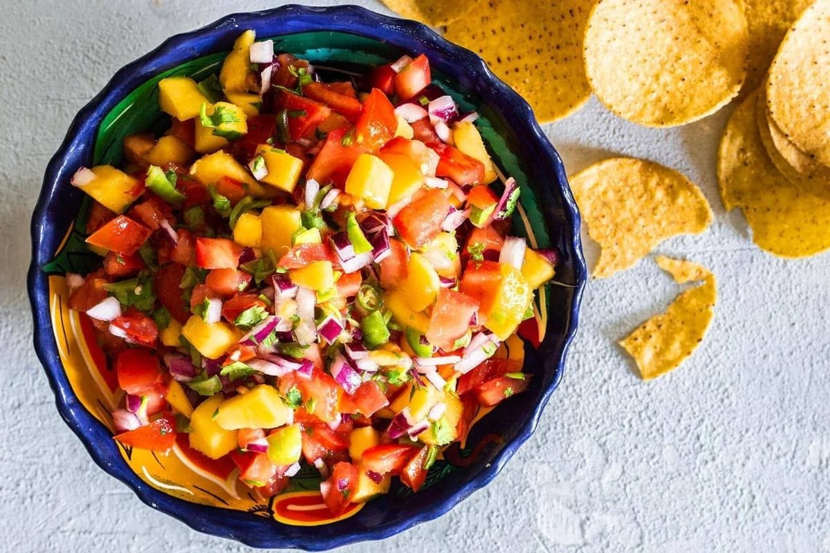 Mango pico de gallo on a bowl with chips on the background.