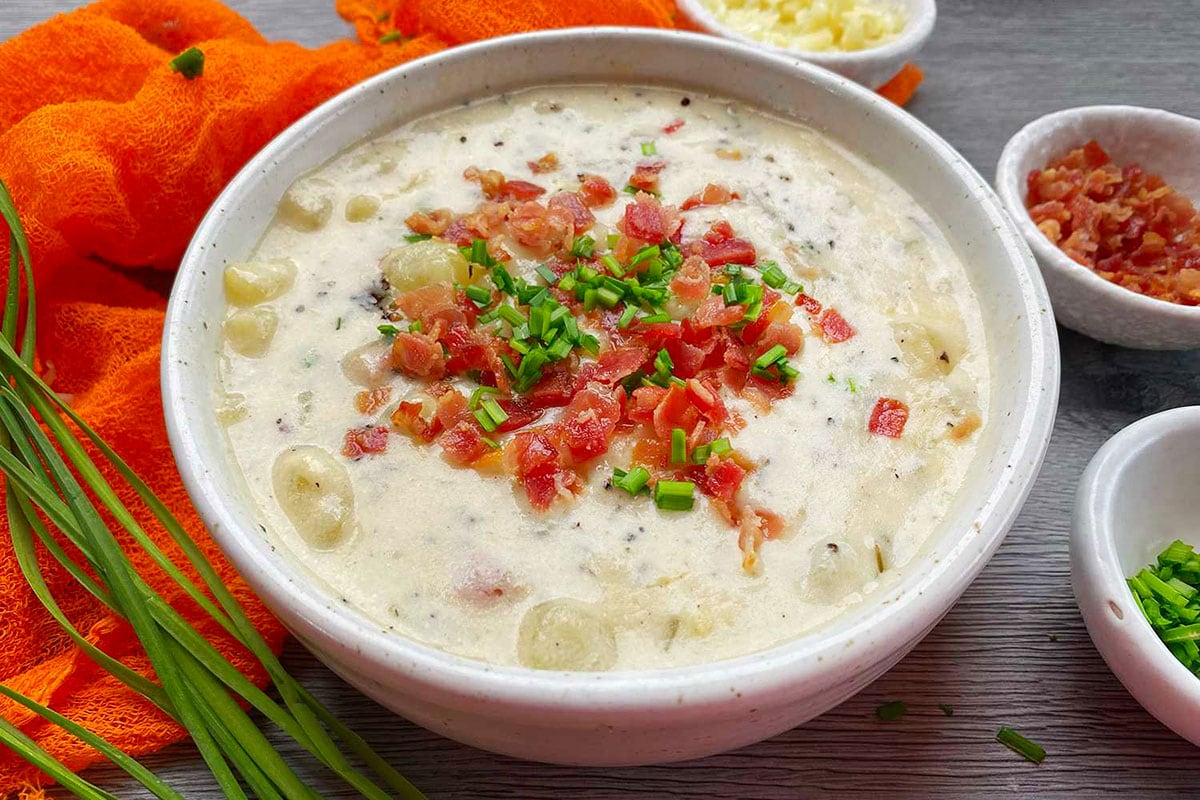 Instant pot potato soup on a bowl with garnish on top.