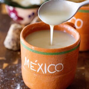 Creamy Oaxacan Atole Blanco de Masa in a cup with a spoon drizzling it.