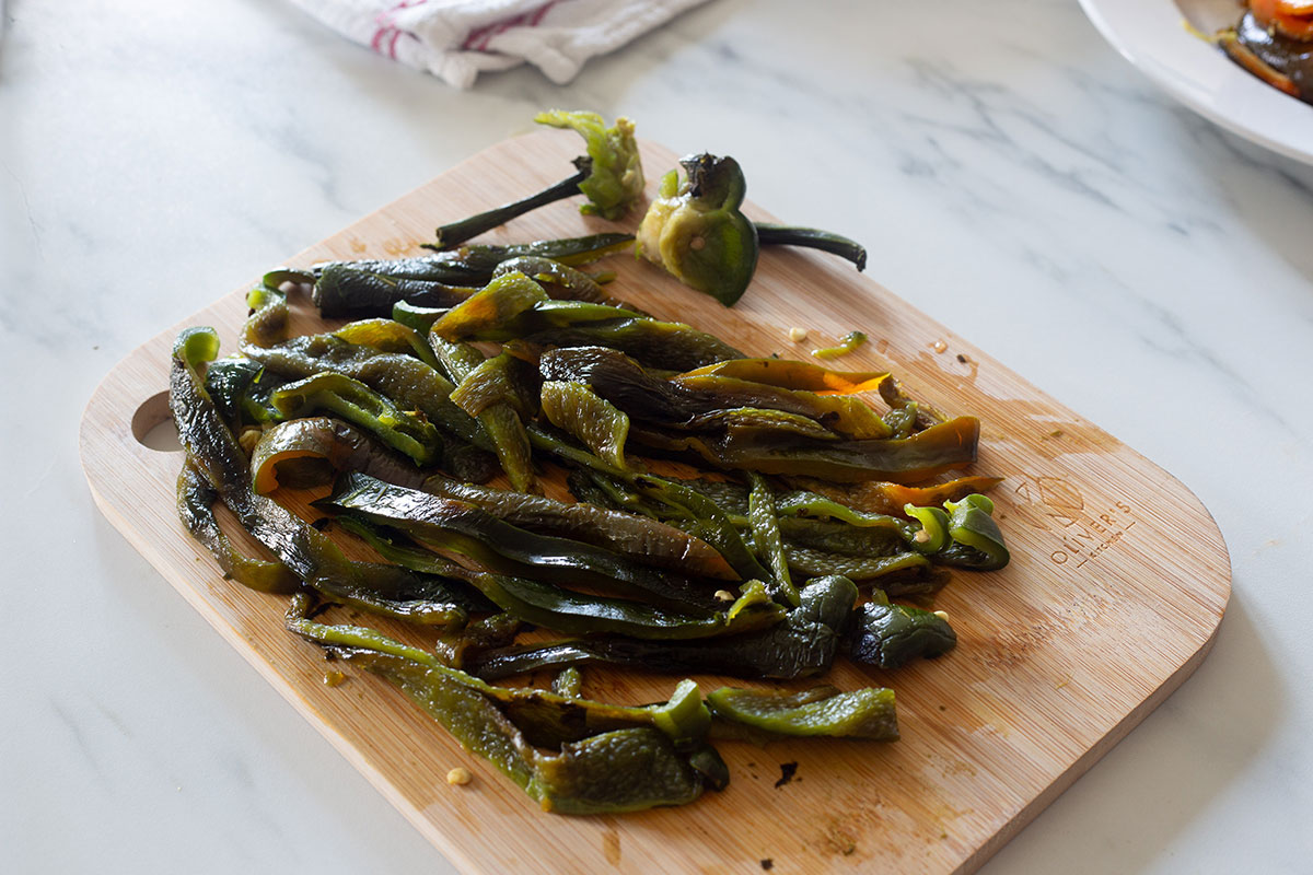 Strips of roasted poblano peppers on a cutting board.