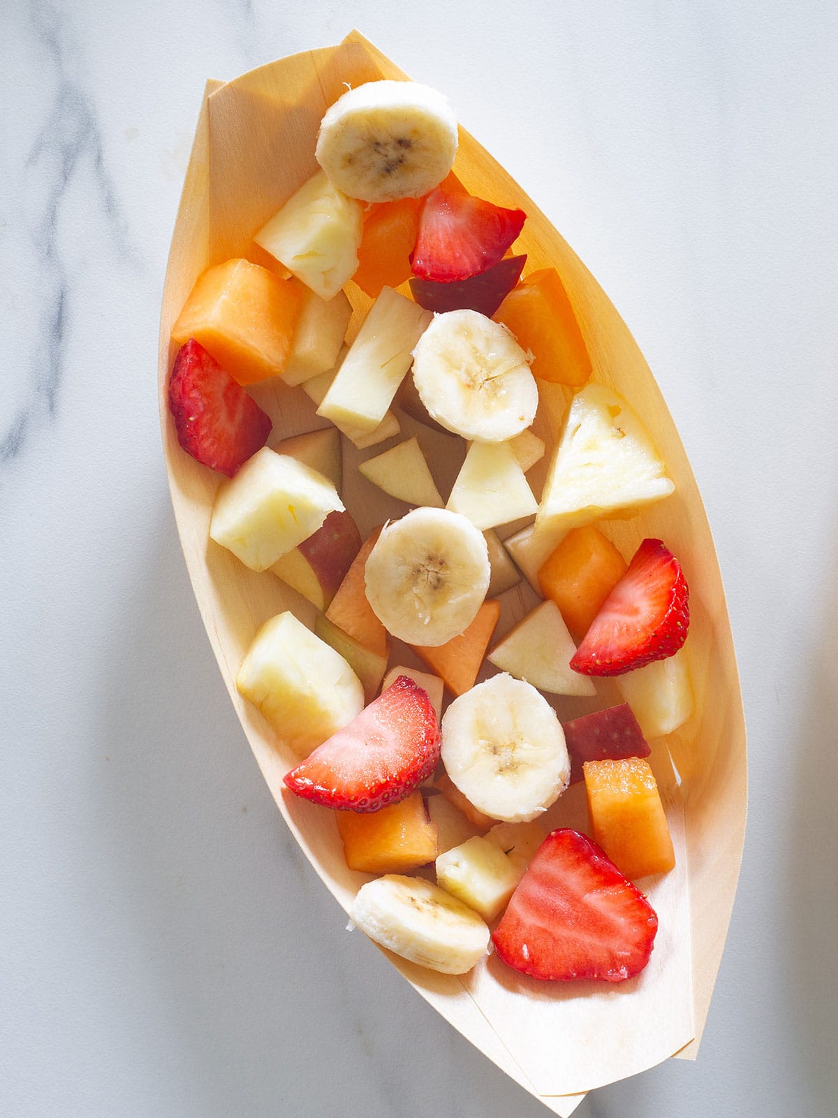 Fruit diced inside a small bamboo boat.