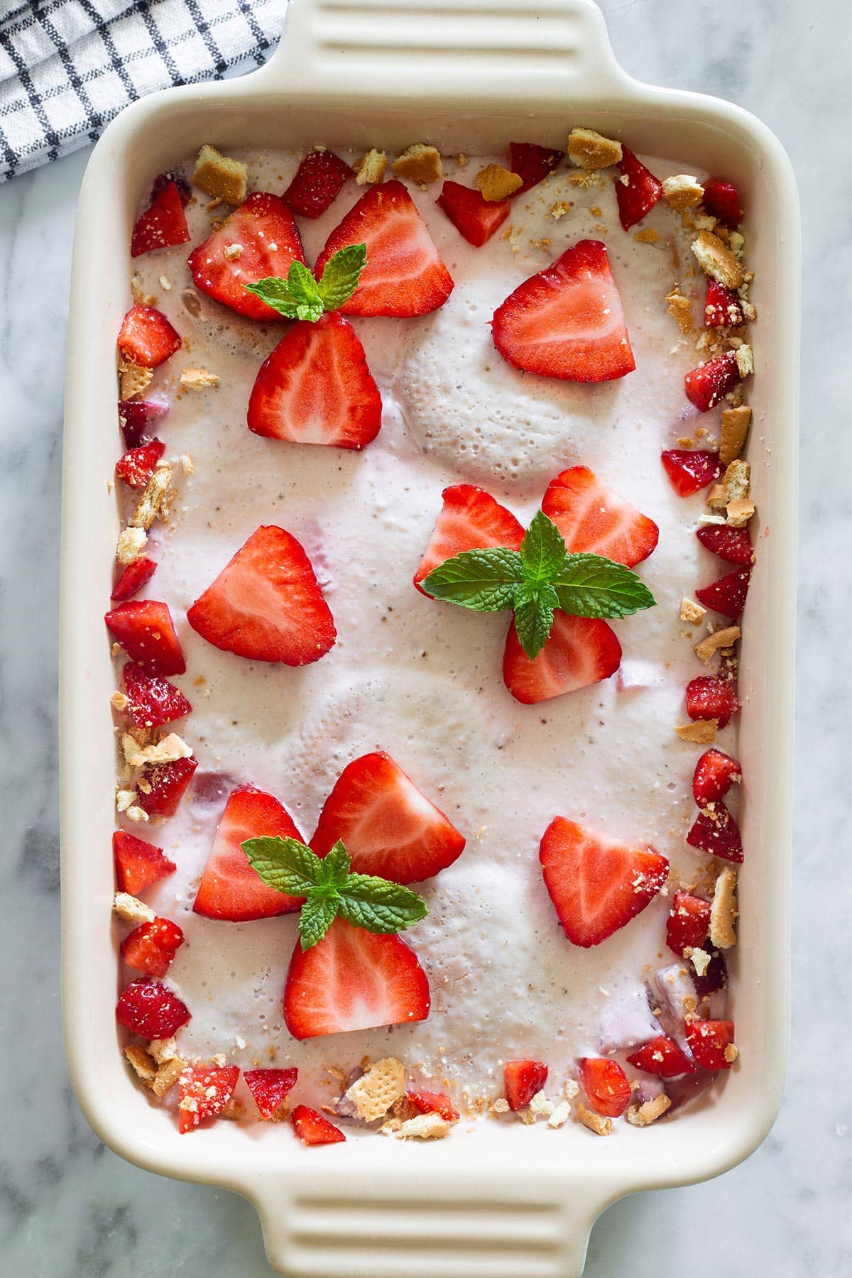 Mexican Carlota de Fresa in a baking dish and decorated with fresh strawberries.