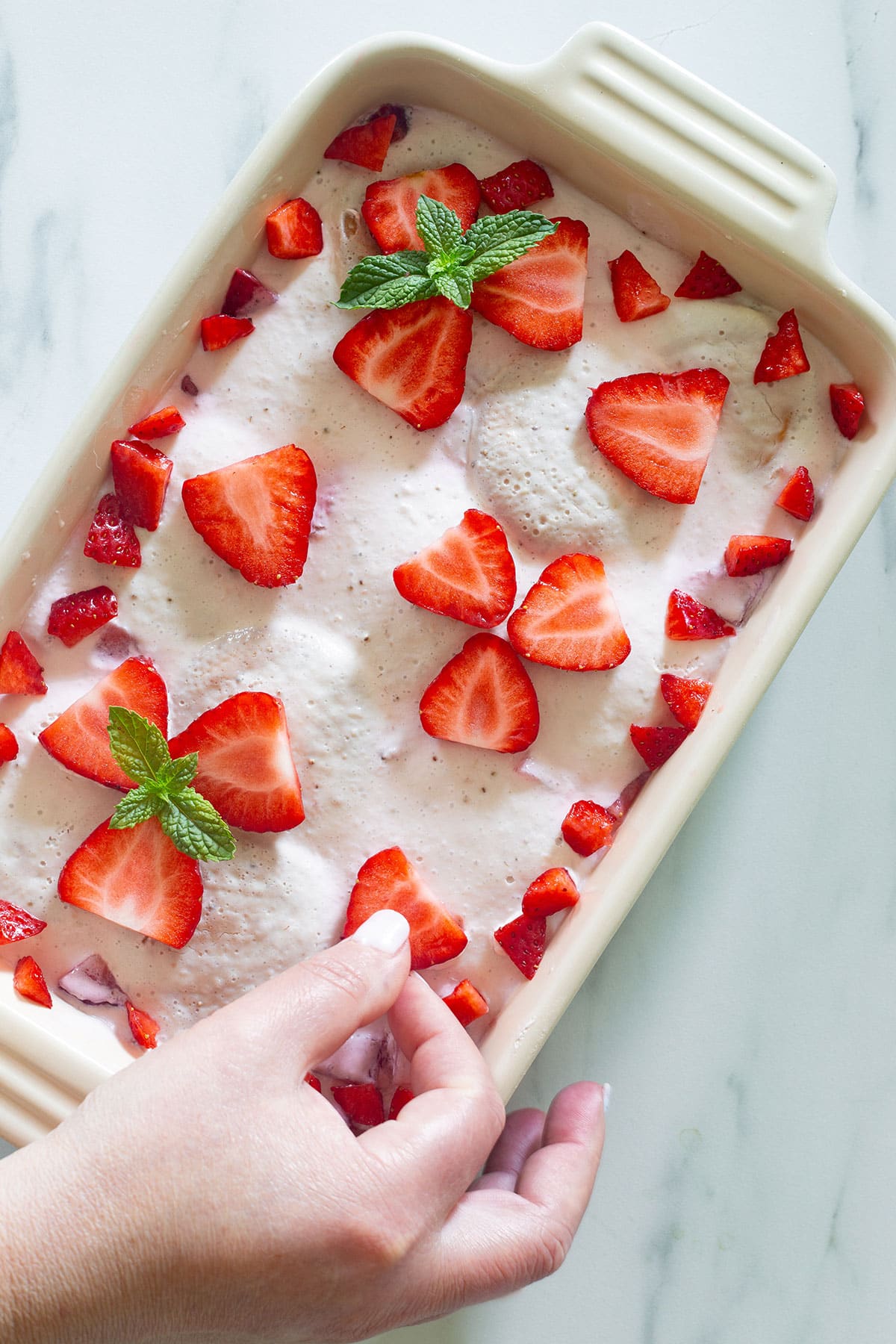 Decorating Carlota de Fresas with fresh strawberries.