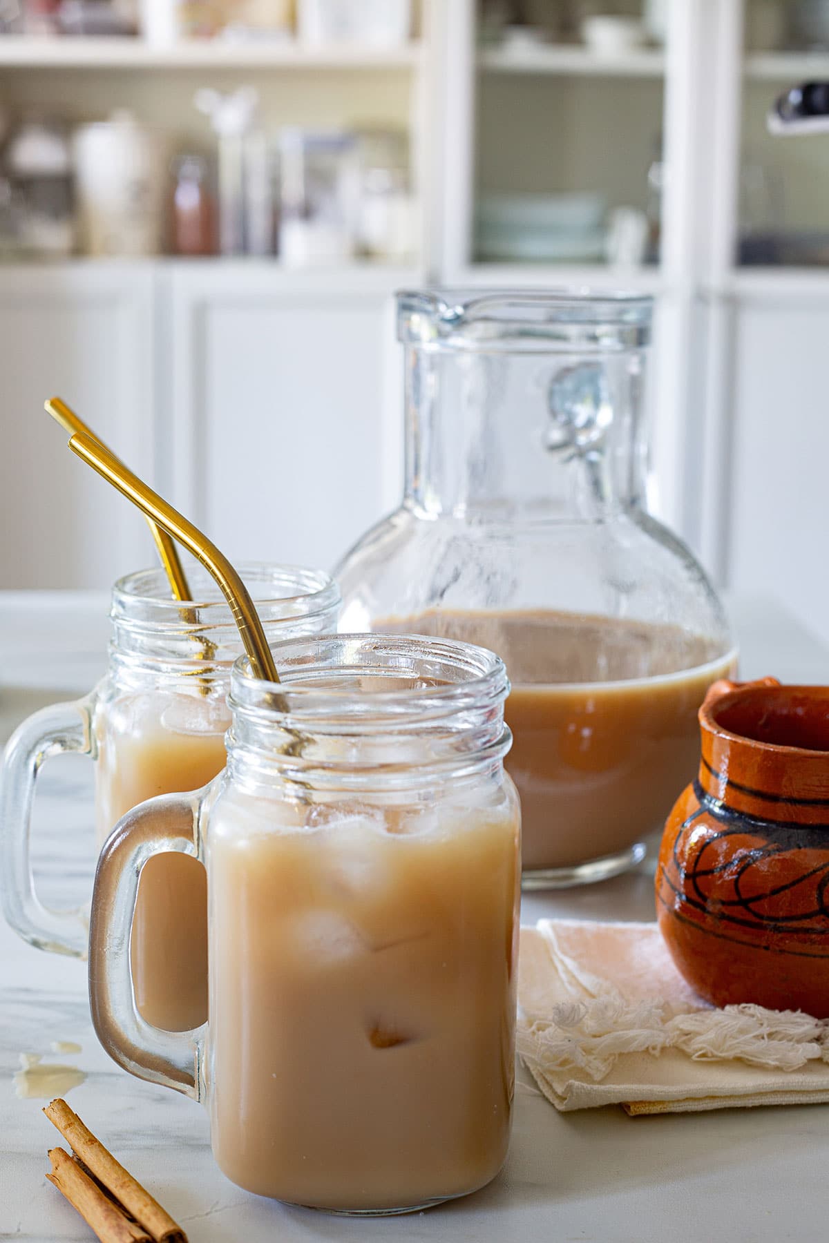 Agua de Café in a cup with ice and a pitcher with more agua fresca behind.