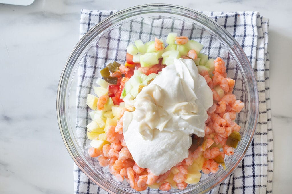 Added cream and mayonnaise to the bowl with vegetables and shrimp.