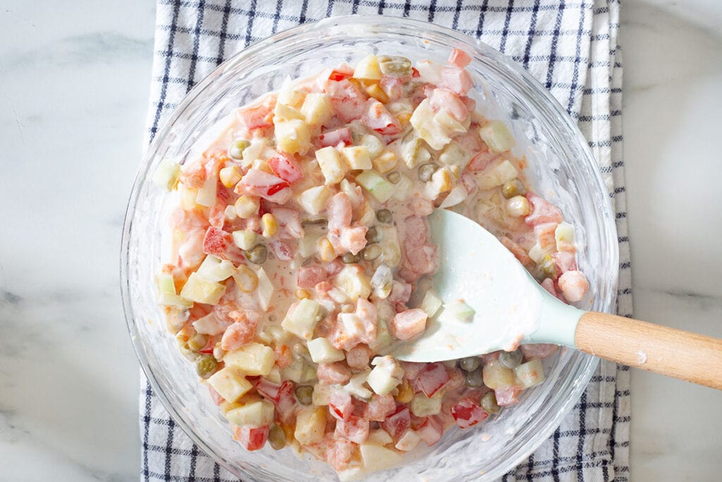 Shrimp, vegetables, and dressing fully combined in a bowl.